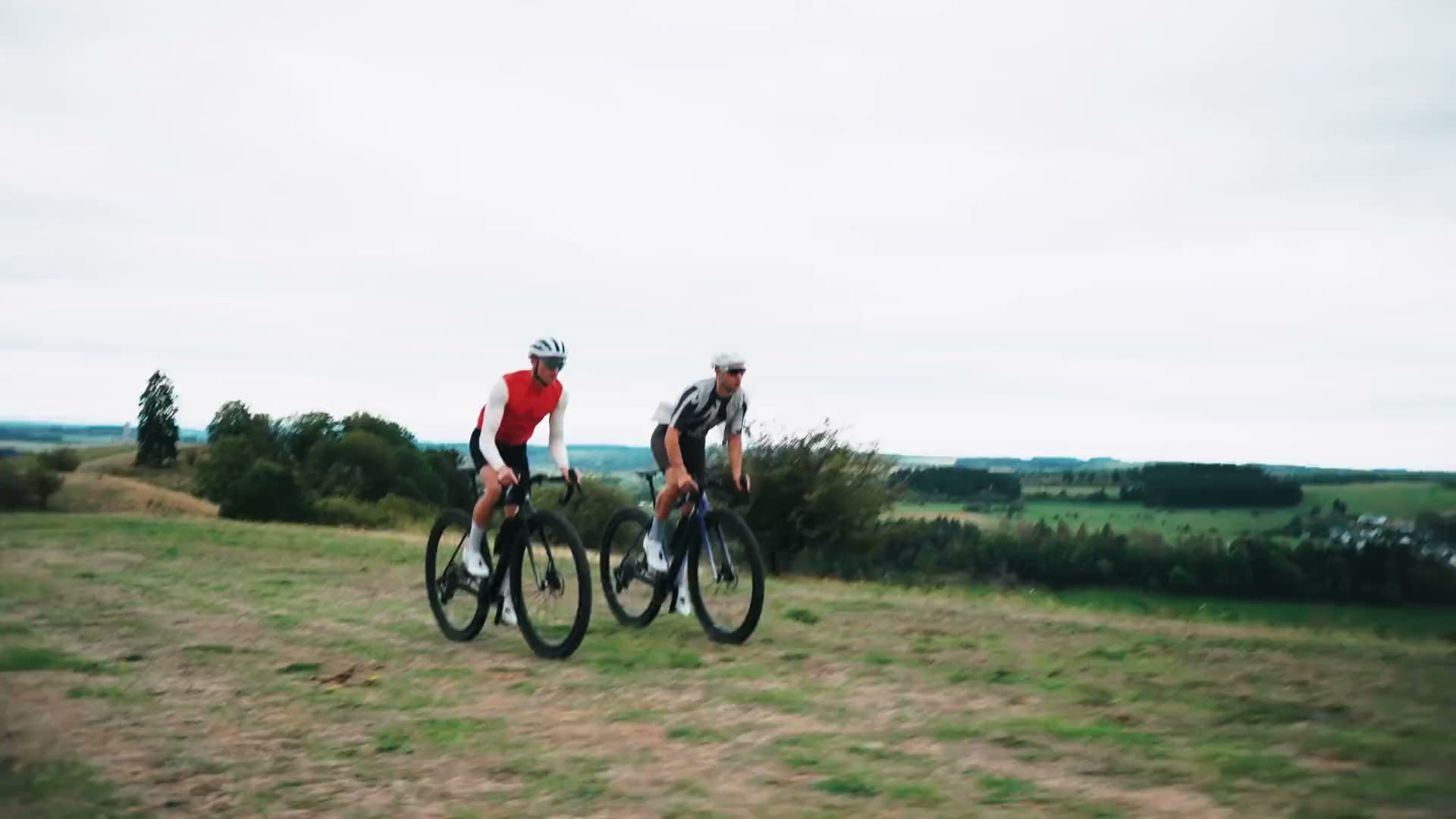 Two riders on gravel bikes on a meadow